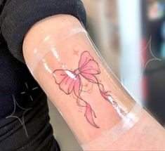 a woman's arm with a pink bow tattoo on the left side of her arm