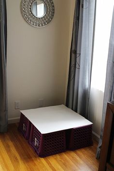 an empty room with a white table and two baskets on the floor in front of it