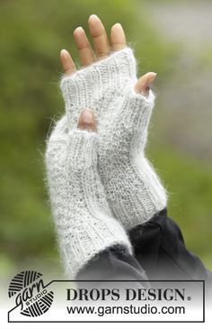 a woman's hand wearing a white knitted fingerless mitt with the words drops design on it