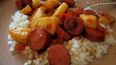 a plate with rice, fruit and sausage on it