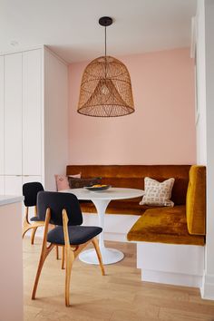 two chairs and a table in a room with pink paint on the walls, wood flooring