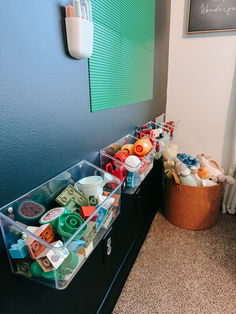 two plastic bins filled with toys on top of a dresser next to a wall