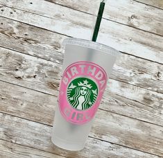 a starbucks cup sitting on top of a wooden table with a straw in the cup