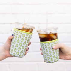 two people holding cups with drinks in them