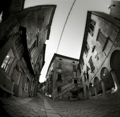 the reflection of buildings in a fish eye lens is shown on an empty cobblestone street