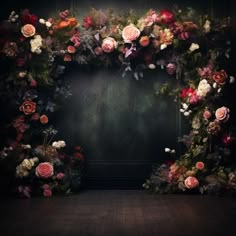 an arrangement of flowers arranged in the shape of a heart on a dark background with wooden floor