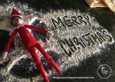 an elf laying on top of a pile of snow with the words merry christmas written in it