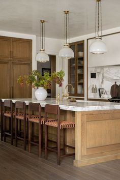 a large kitchen with wooden cabinets and marble counter tops, along with bar stools