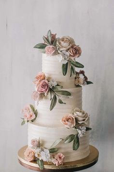 a three tiered cake with flowers on the side and leaves on the top layer