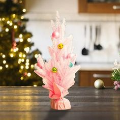 a small pink christmas tree sitting on top of a wooden table