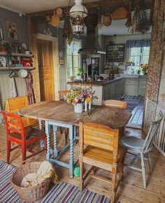 a kitchen table and chairs with baskets on the floor next to it in front of a window