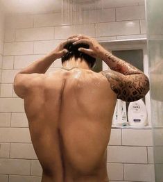 a man with his back turned to the camera in front of a shower head and arm