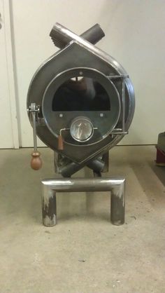 an old fashioned stove sitting on top of a metal stand next to a white wall