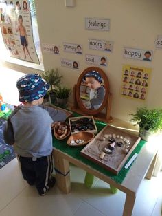 a young boy standing in front of a table filled with rocks and stones on it