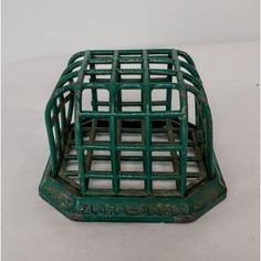 a green metal cage sitting on top of a white table