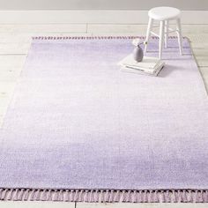 a purple rug with tassels and a white chair on the floor next to it