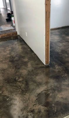 an empty room with white walls and brown flooring in the process of being painted