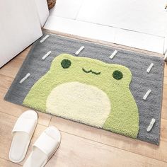 a pair of slippers sitting on the floor next to a rug with a frog