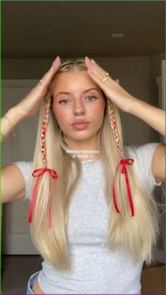 a woman with long blonde hair is holding her hands up to her head and wearing red bows