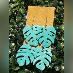 the earrings are made out of wood and have blue leaves on them, as well as green foliage