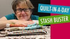 a woman sitting at a table with quilt - in - a - day on it