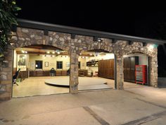 an open garage door at night with lights on the outside and stone walls around it