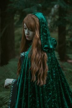 a woman with long red hair wearing a green cloak