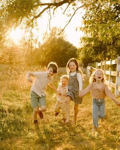 four children running in the grass with their arms around each other and one child holding hands