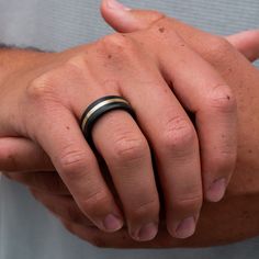 a man's hand with a black ring on it, showing the middle finger