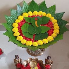 a vase filled with yellow and red flowers sitting on top of a table next to other decorations