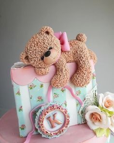 a teddy bear sitting on top of a pink cake