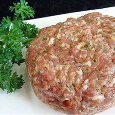 a hamburger sitting on top of a white plate next to parsley