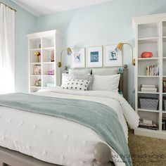 a bedroom with blue walls, white bedding and bookshelves on the wall