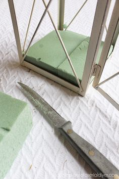 a pair of scissors sitting on top of a bed next to a green pillow and blanket