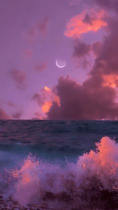 the moon is setting over the ocean with pink clouds