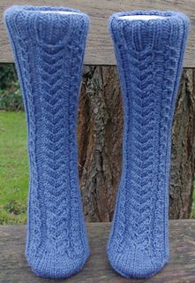 two blue knitted socks sitting on top of a wooden bench next to a tree