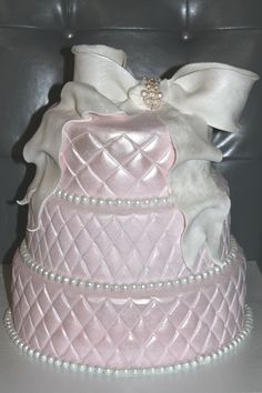 a three tiered wedding cake decorated with pearls and bows