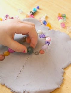 a child's hand on a piece of paper with beads