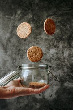 a person holding a glass jar with some cookies in it and falling into the air