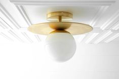 a light fixture hanging from the ceiling in a room with white walls and wood flooring