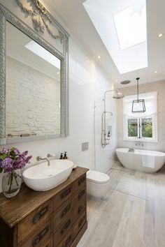 a large bathroom with a skylight above the bathtub and sink, along with a wooden dresser