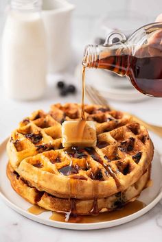 syrup being poured onto a waffle on a plate