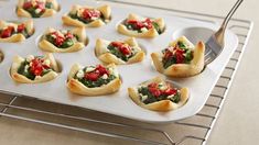 small appetizers with spinach and red peppers are on a baking sheet