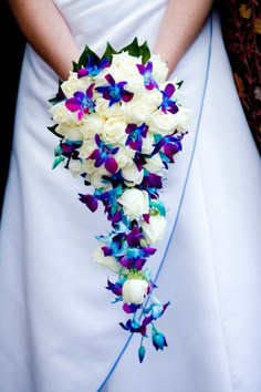 a bride holding a bouquet of purple and white flowers