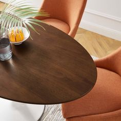 a round table with two chairs and a bowl of fruit on it, in the middle of a living room