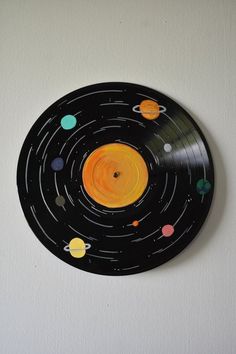 a black and yellow record with planets painted on it's side in the shape of a circle