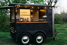 a black food truck with lights on it's side in the middle of a field