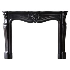 an ornate black fireplace mantel with carvings on the top and sides, in front of a white background