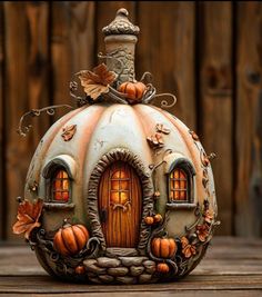 a small pumpkin shaped house with windows and leaves on it's roof, sitting on a wooden surface