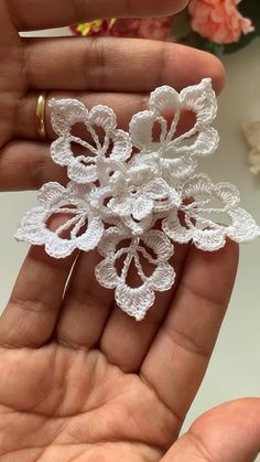 a hand holding a small white flower brooch